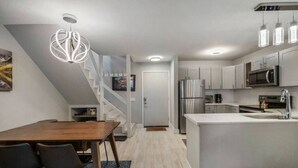 Een moderne keuken met een centraal eiland, roestvrijstalen apparatuur en een trap naar een hoger niveau.