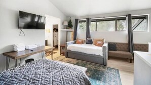 Een moderne hotelkamer met een groot bed, een bureau, een bank en een aan de muur bevestigde televisie.