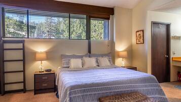 Une chambre à coucher avec un lit, deux lampes de chevet, une échelle en bois, un petit banc et une porte.