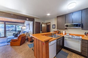 A modern kitchen with a central island, built-in appliances, and dark wooden cabinets.