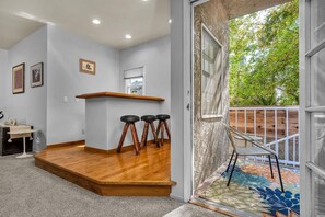 Eine moderne Küche mit einer Holztheke, Barhocker und Blick auf einen Balkon mit Geländer.