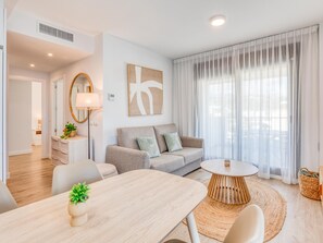 A modern living room with a sofa, a dining table, and a round coffee table. - Modern Penthouse in Estepona with parking and stunning views (Estepona)