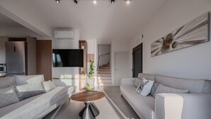 Una sala de estar moderna con un sofá, una mesa de centro y un televisor de pantalla plana montado en la pared.