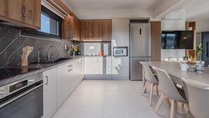 Una cocina moderna con encimeras de mármol oscuro, armarios de madera y un refrigerador de acero inoxidable.