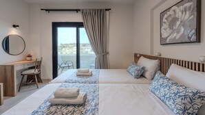 Habitación de hotel con cama, escritorio, silla, ventana con cortinas y un cuadro en la pared.