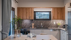 Una cocina moderna con armarios de madera, horno empotrado y comedor con mesa y sillas.