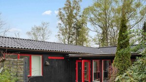 Un petit bâtiment à l’extérieur noir et aux fenêtres à cadre rouge, portant l’inscription « LIS’PETERS’BO ».