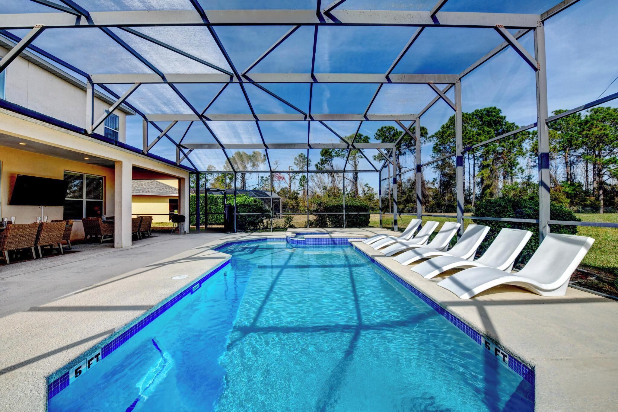 A swimming pool with lounge chairs and a covered area.