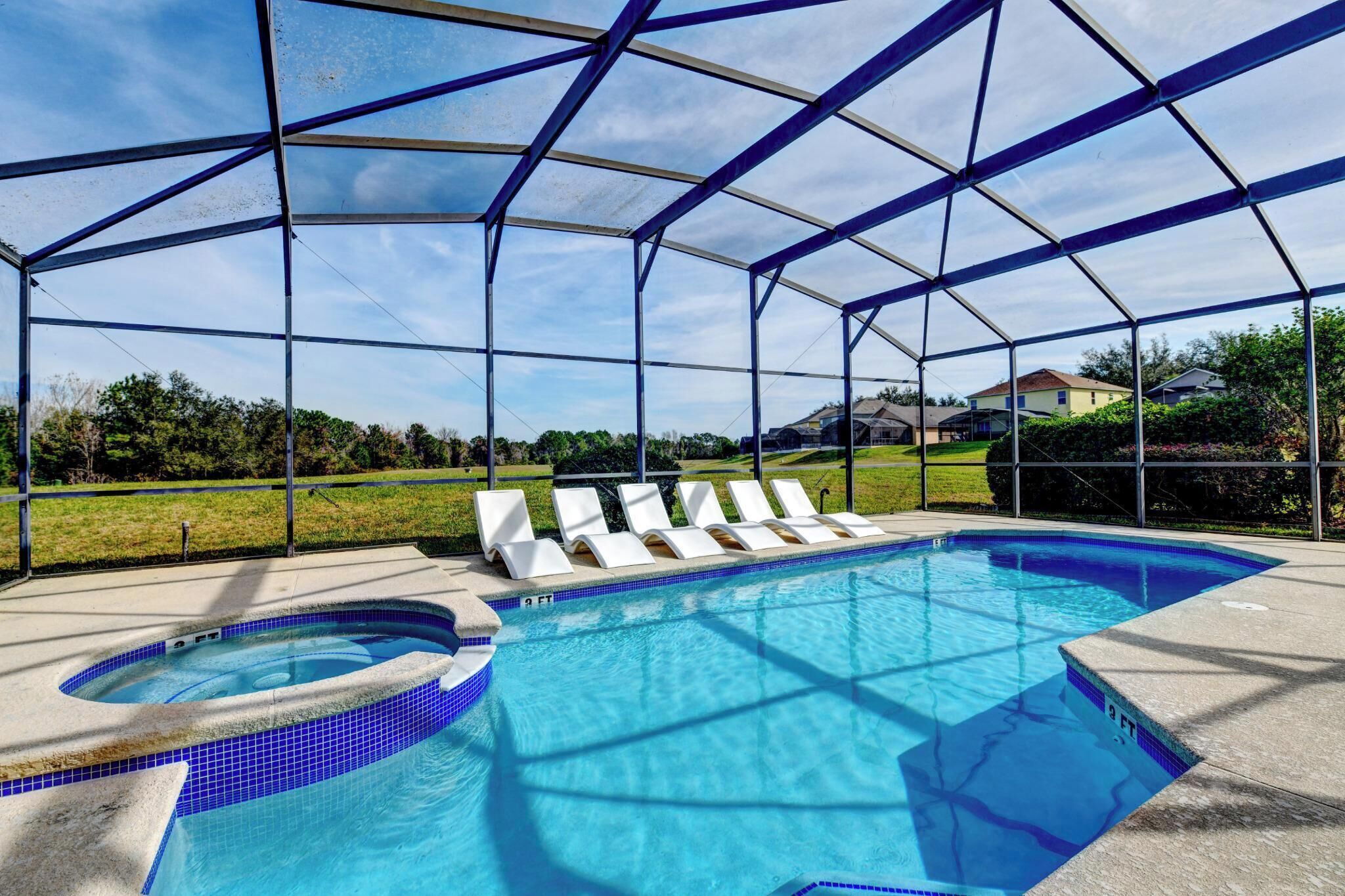 Una piscina exterior techada con sillas de descanso y un jacuzzi.