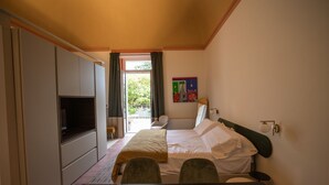 Quarto com cama, televisão, escrivaninha e vista para o exterior.