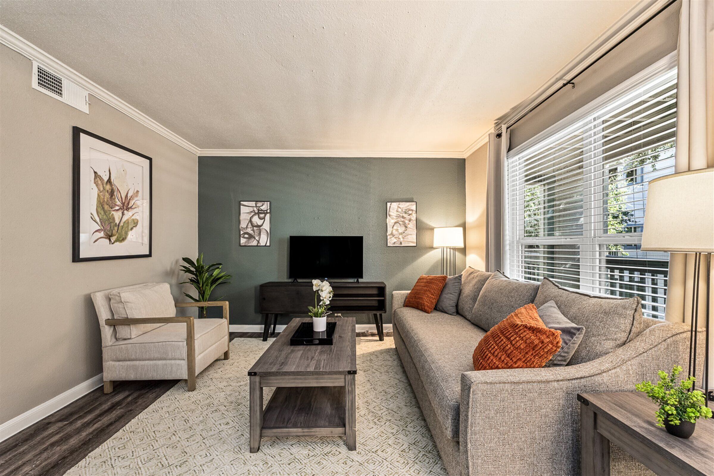 A living room with a sofa, armchair, coffee table, and a flat-screen TV.