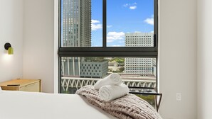 A hotel room with a large window, a bed, a small table, and a towel on the bed. - City Views Downtown Miami (Miami)