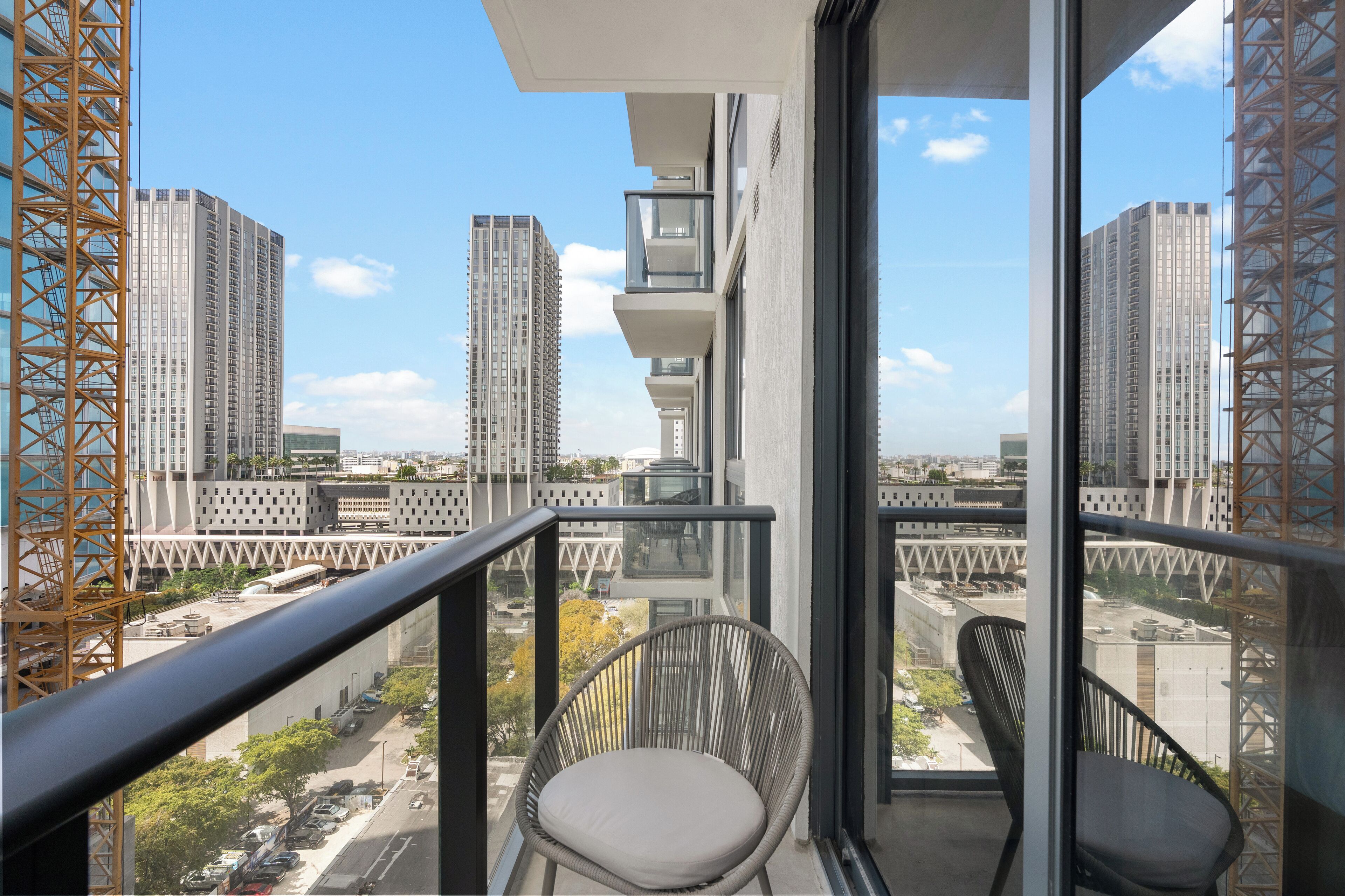 Un balcón con vistas a edificios altos y una grúa de construcción.
