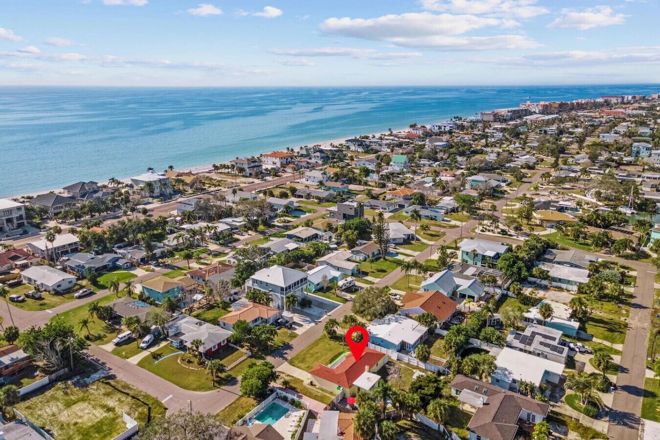 An aerial view of a coastal residential area with houses, roads, and a beach.