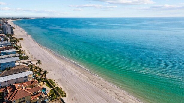 Un hotel frente al mar con vista a la playa, que cuenta con una extensa playa de arena y el océano.
