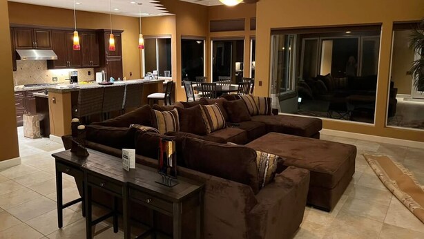 A spacious living area with a brown sectional sofa, a dining table, and a kitchen in the background. - Gorgeous house with private pool/hot tub in a gated community in Bermuda Dunes. (Bermuda Dunes)