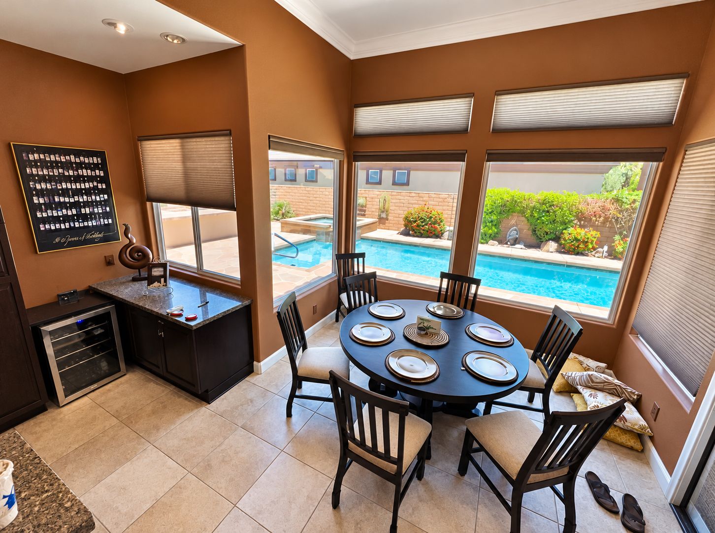 A dining area with a pool view, a kitchen with a built-in oven, and a large window with blinds.