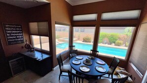 A dining area with a round table, chairs, and a view of a swimming pool. - Gorgeous house with private pool/hot tub in a gated community in Bermuda Dunes. (Bermuda Dunes)