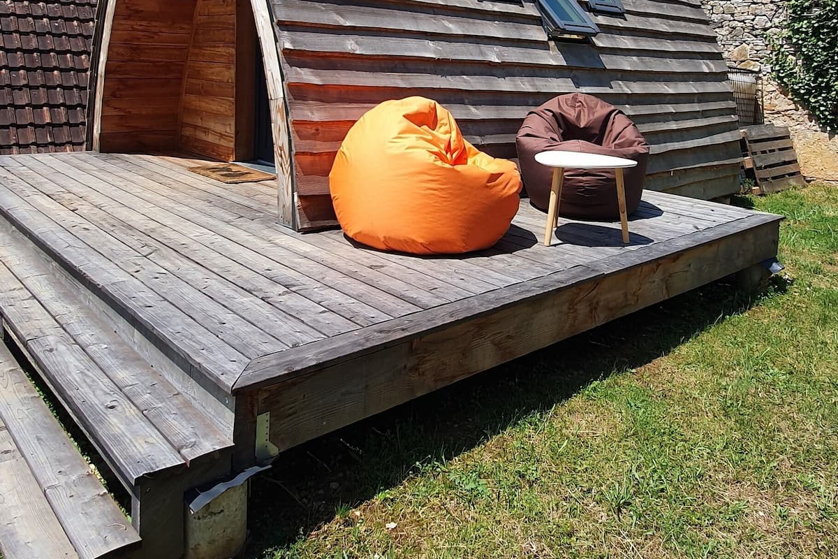 A wooden cabin with a sloped roof, a deck, and two bean bags.