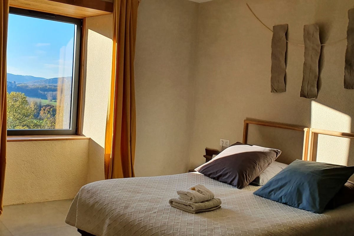 A bedroom with a bed, pillows, and a window with curtains.