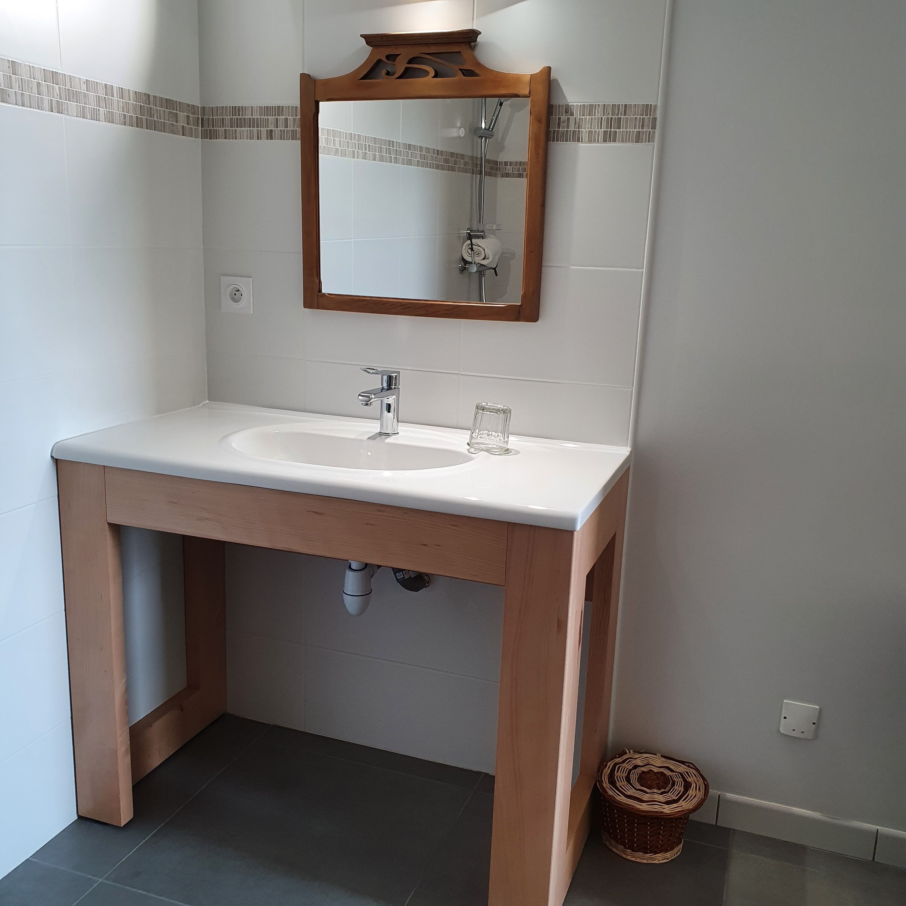 A bathroom with a white sink, wooden vanity, and a mirror with a wooden frame.