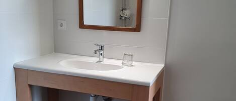 A bathroom with a white sink, wooden vanity, and a mirror with a wooden frame.