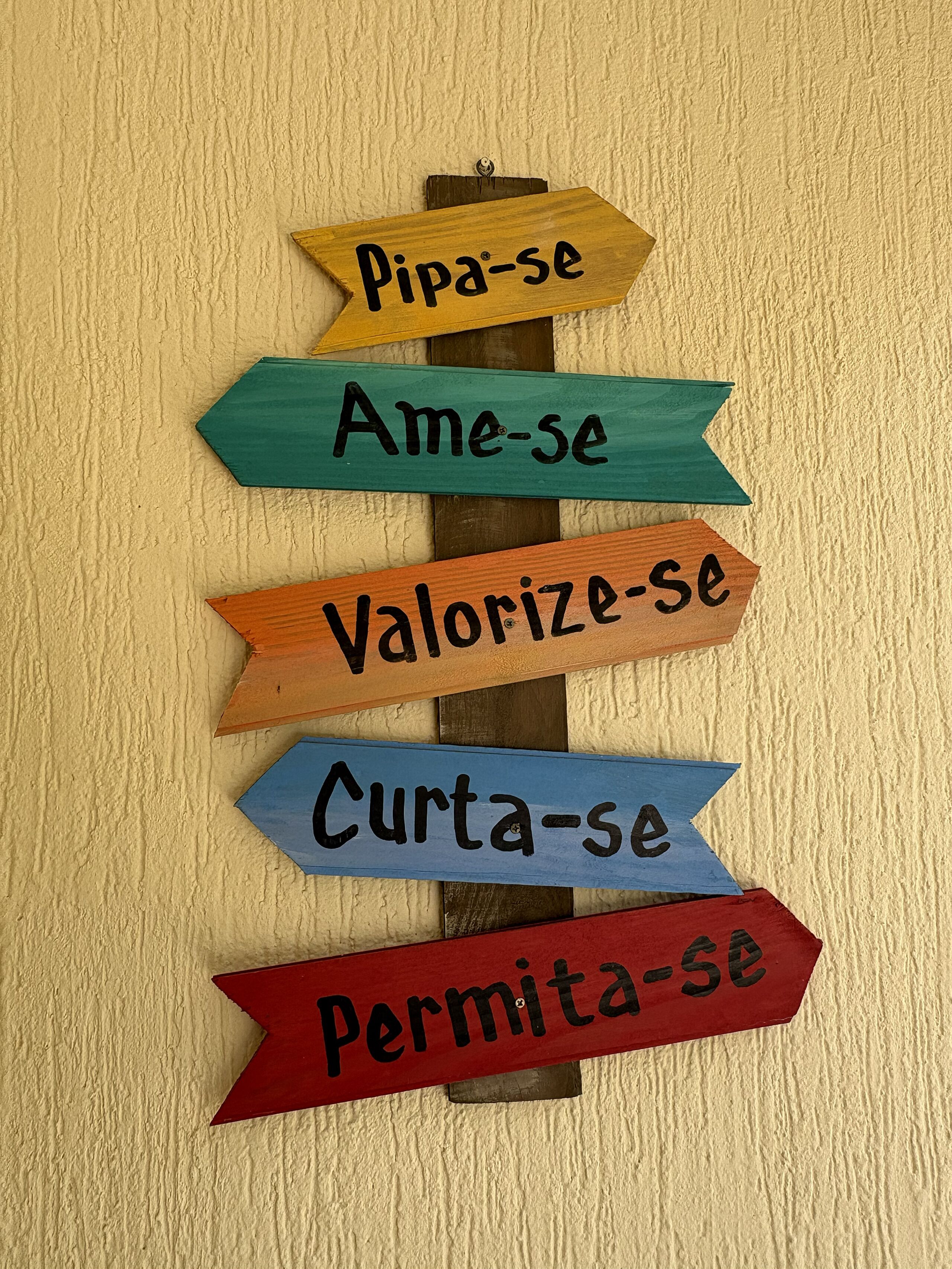 Ein hölzernes Schild mit Pfeilen, die in verschiedene Richtungen zeigen, wobei jede Pfeilbeschriftung ein spanisches Wort trägt.