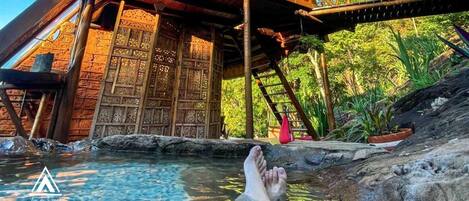 A wooden structure with a pool, surrounded by greenery.