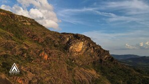 A mountainous landscape with a prominent rocky cliff and a clear sky. - Chalé Tipi da Serra (Brumadinho)