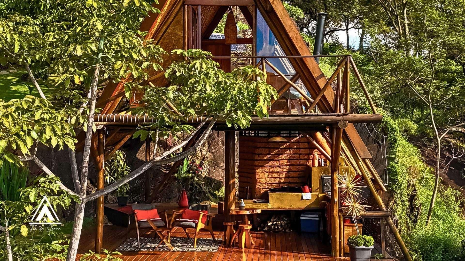 Una cabaña de madera rústica con un porche, mobiliario exterior y una pequeña mesa.