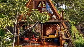 A rustic wooden cabin with a deck, outdoor seating, and a small table. - Chalé Tipi da Serra (Brumadinho)