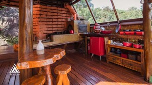 Eine rustikale Holzhütte mit einer Ziegelwand, einem Kaminofen und einem Regal mit roten Töpfen.