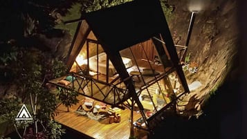A treehouse with a wooden floor, a bed, and a small table.