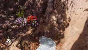A rocky terrain with a small waterfall and flowering plants. - Chalé Tipi da Serra (Brumadinho)