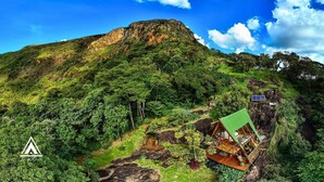 A mountain with a green-roofed cabin and a solar panel. - Chalé Tipi da Serra (Brumadinho)