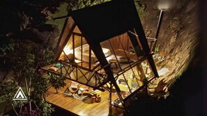 Una casa en un árbol con piso de madera, una cama y una pequeña mesa.