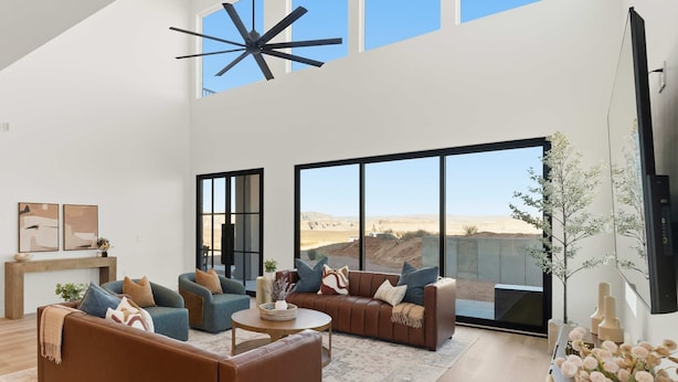 A spacious living room with large windows, a ceiling fan, and a flat-screen TV. - The Lookout- Luxe, Hot Tub, Firepit, 50-Mile Views (Page)