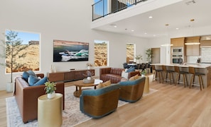 A modern living room with a sofa, coffee table, and a dining area with bar stools.