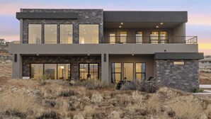 A modern two-story house with large windows, a balcony, and a stone facade. - The Lookout- Luxe, Hot Tub, Firepit, 50-Mile Views (Page)
