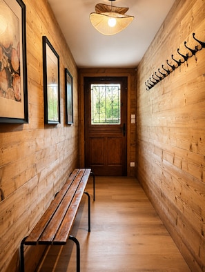 A wooden hallway with a bench, a door with a window, and wall-mounted hooks. - Maison Maneki - Chalet Évasion for 10 people on the edge of a magnificent pond (Ban-sur-Meurthe-Clefcy)