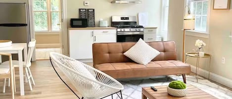 A modern living room with a sofa, a coffee table, and a dining area.