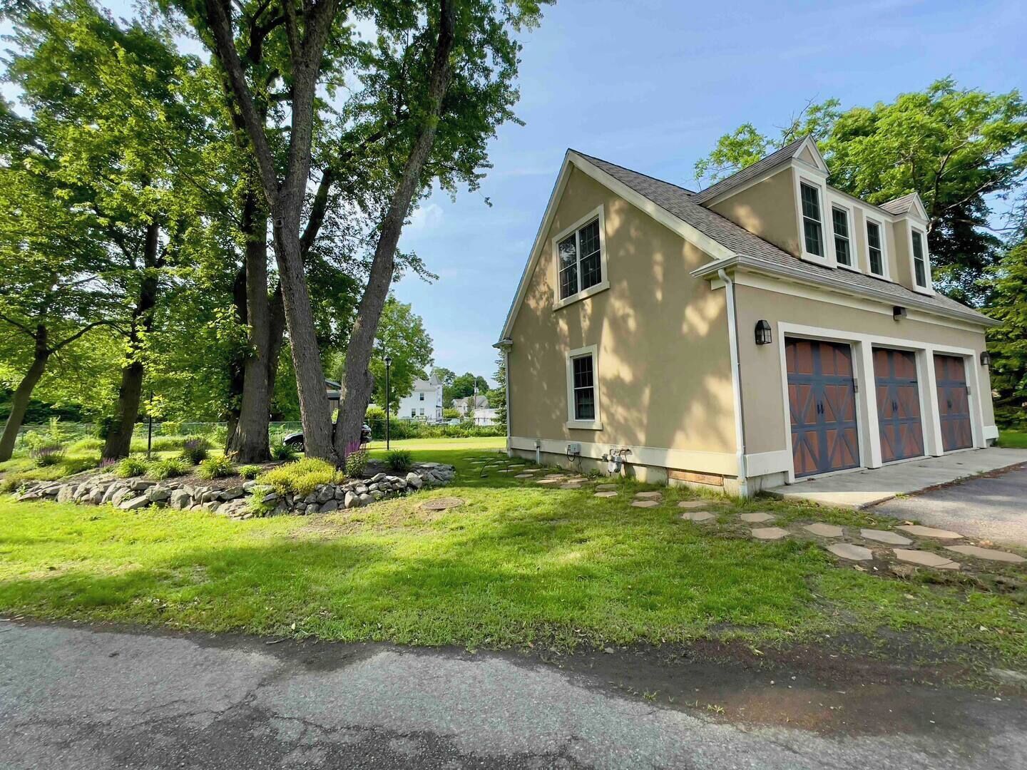 A two-story house with a garage, surrounded by a well-maintained lawn and trees.
