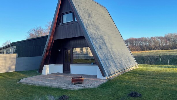 Une maison moderne avec un toit en pente, une grande fenêtre et un petit espace porche.