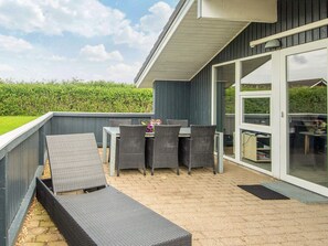An outdoor patio with a table and chairs, a sofa, and a sliding glass door leading to an indoor area. - 6 Person Holiday Home in Hemmet (Hemmet)