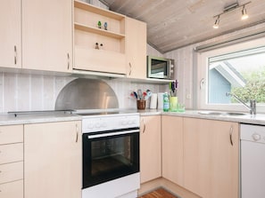 A kitchen with a stove, microwave, and a window with a view of the outside. - 6 Person Holiday Home in Hemmet (Hemmet)