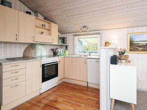 Eine Küche mit Holzausstattung, einer Mikrowelle, einem Backofen, einem Geschirrspüler und einem Fenster mit Blick.