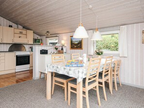 A cozy kitchen with wooden cabinets, a dining table with chairs, and a window with a view of greenery. - 6 Person Holiday Home in Hemmet (Hemmet)