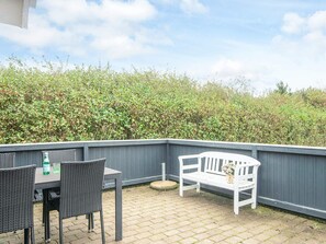 An outdoor patio with a table and chairs, a bench, and a hedge in the background. - 6 Person Holiday Home in Hemmet (Hemmet)