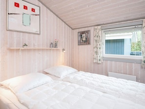 A bedroom with a bed, a window with curtains, a wall-mounted shelf with decorative items, and a framed picture. - 6 Person Holiday Home in Hemmet (Hemmet)