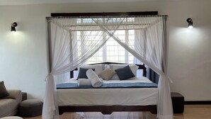 Une chambre spacieuse avec un grand lit, un baldaquin et une vue sur l’extérieur.